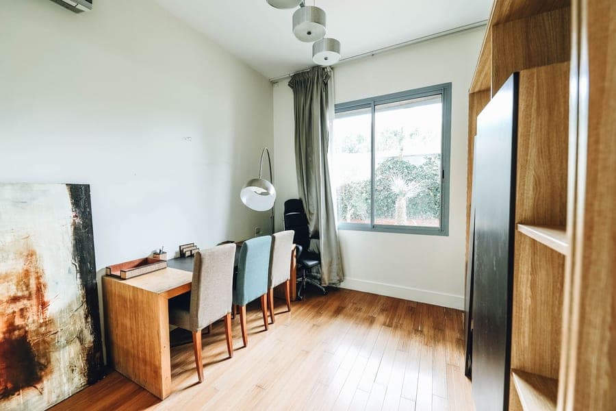 Petit bureau au parquet clair : postes de travail en bois alignés devant une grande fenêtre