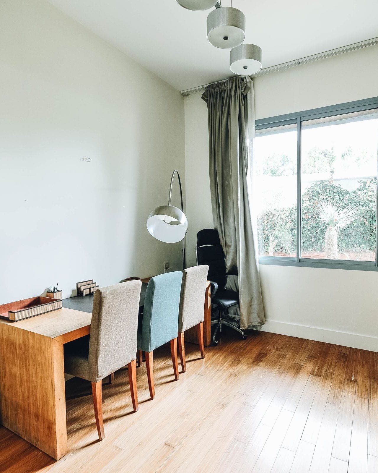 Pièce de bureau au parquet clair : postes de travail en bois alignés sous une grande fenêtre