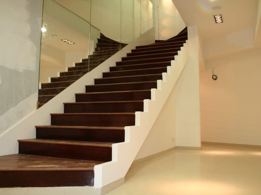 Escalier aux marches en bois foncé sur limon blanc, mur habillé de miroir, sol blanc brillant