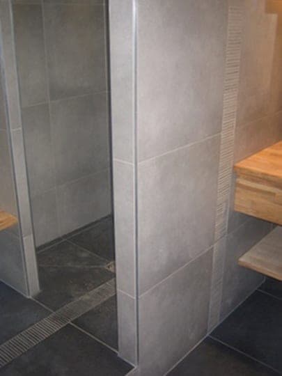 Douche à l'italienne : grands carreaux gris, caniveau inox au sol et tablette en bois