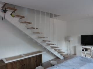 Séjour blanc : escalier aux marches en bois suspendues par des tiges, meuble bas en bois dessous