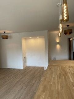 Mur blanc creusé d'une niche éclairée, suspensions en verre ambré et parquet de chêne clair