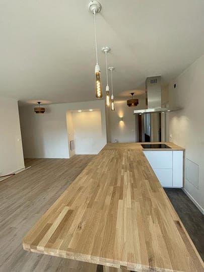 Cuisine ouverte : plateau en chêne massif, suspensions en verre, hotte inox et façades blanches