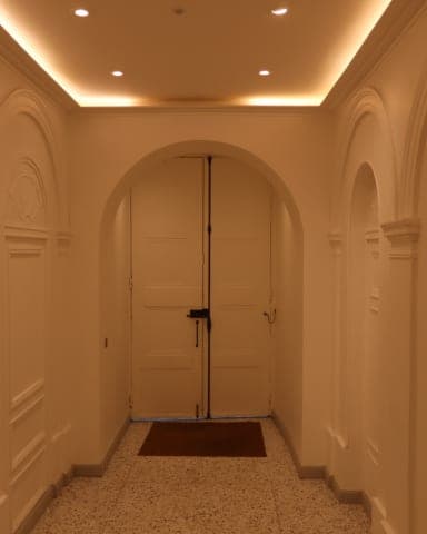 Arcades et panneaux moulurés peints d'un hall, double porte en arc, éclairage chaud