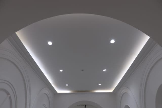 Plafond bordé d'une gorge lumineuse et de spots entre deux arcades moulurées blanches